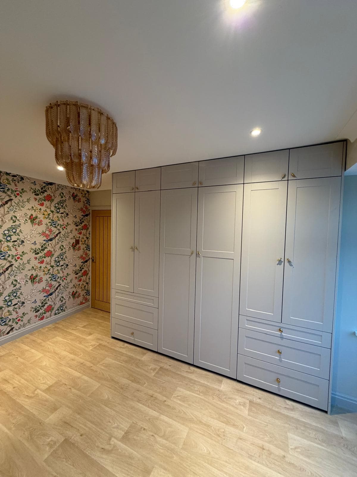 Fitted bedroom wardrobes in dove-grey shaker style with brass handles